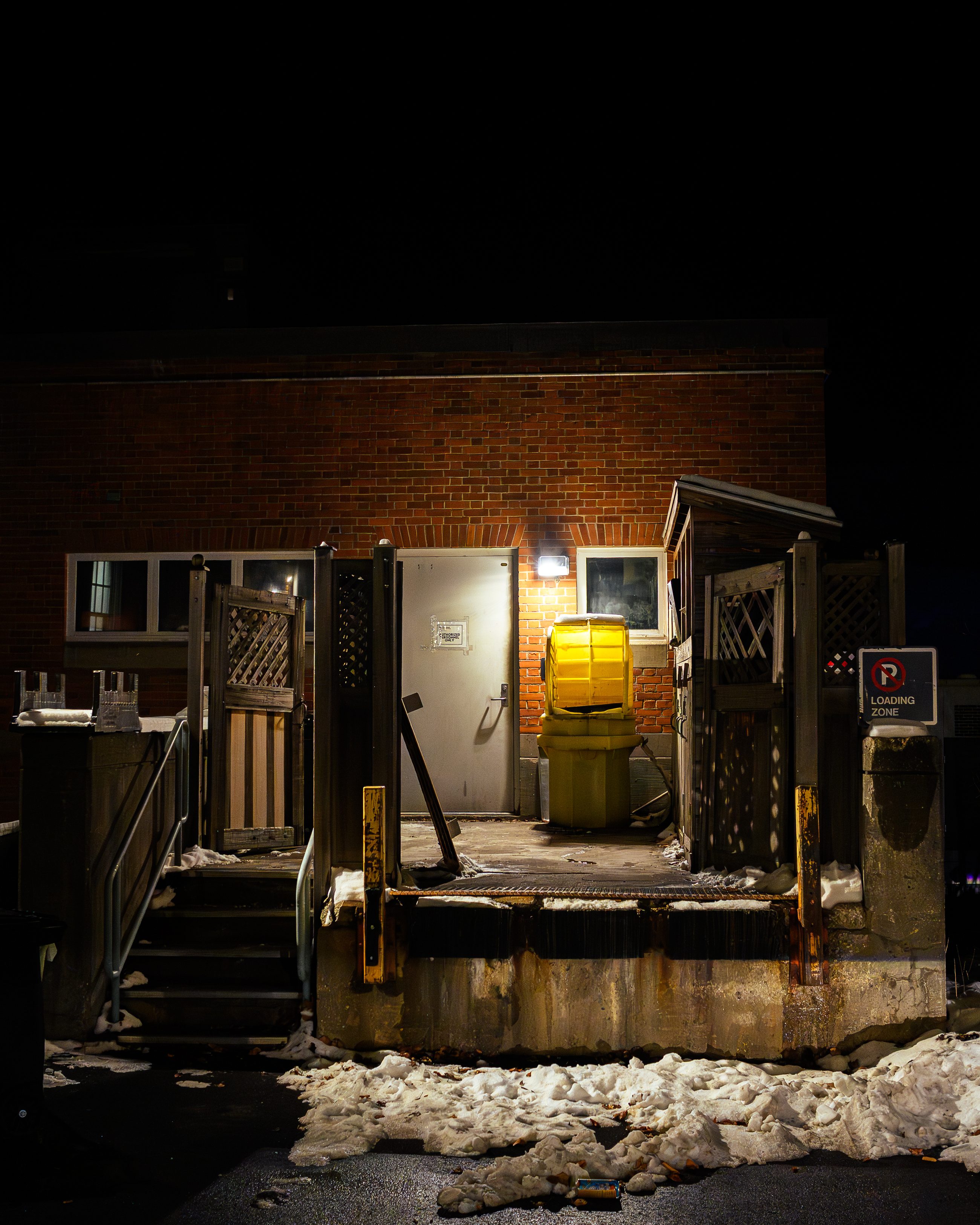 The same yard a few steps along, a yellow waste bin beside the loading steps.