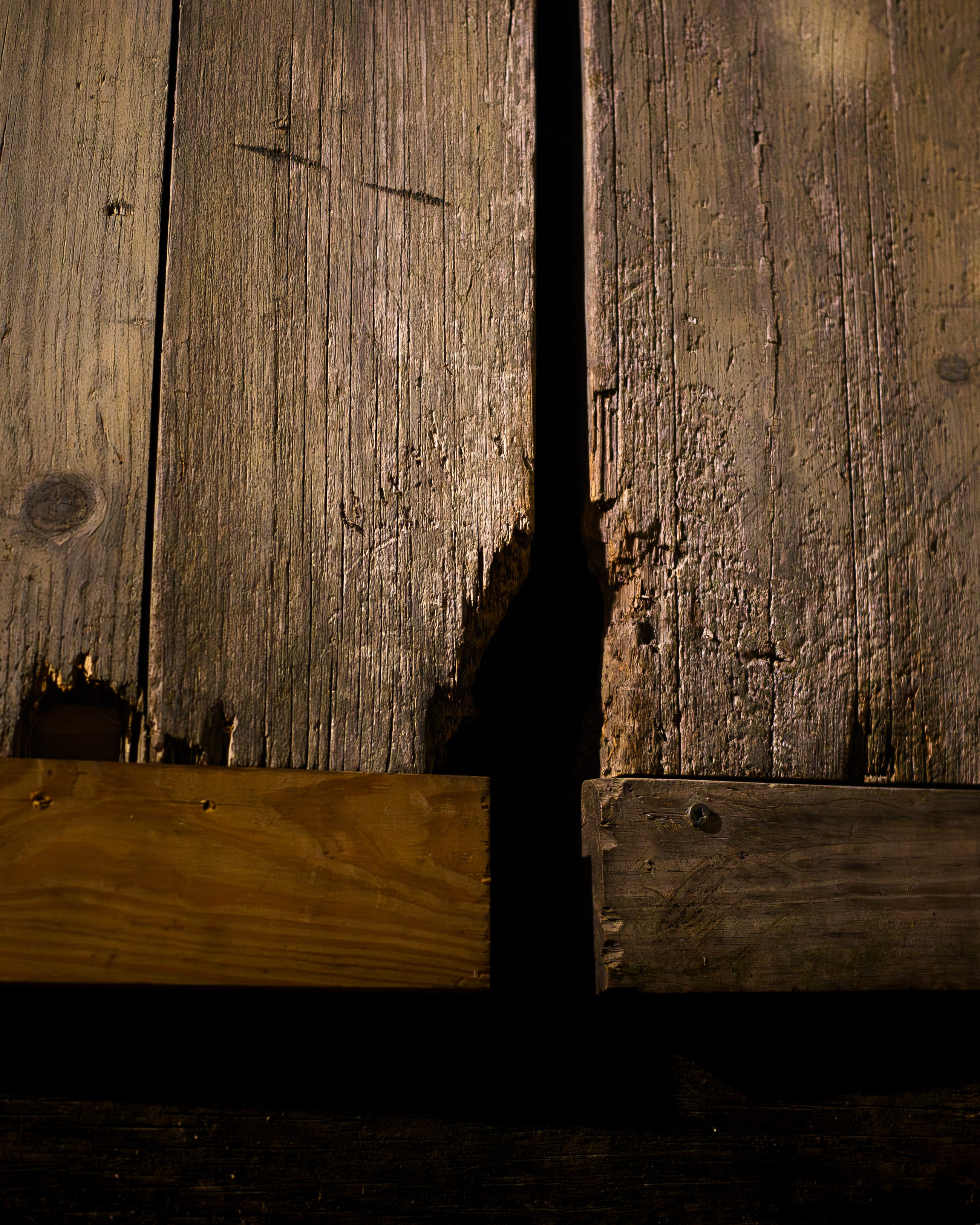 Split and cupped boards with a sheet of plywood screwed over the gap.