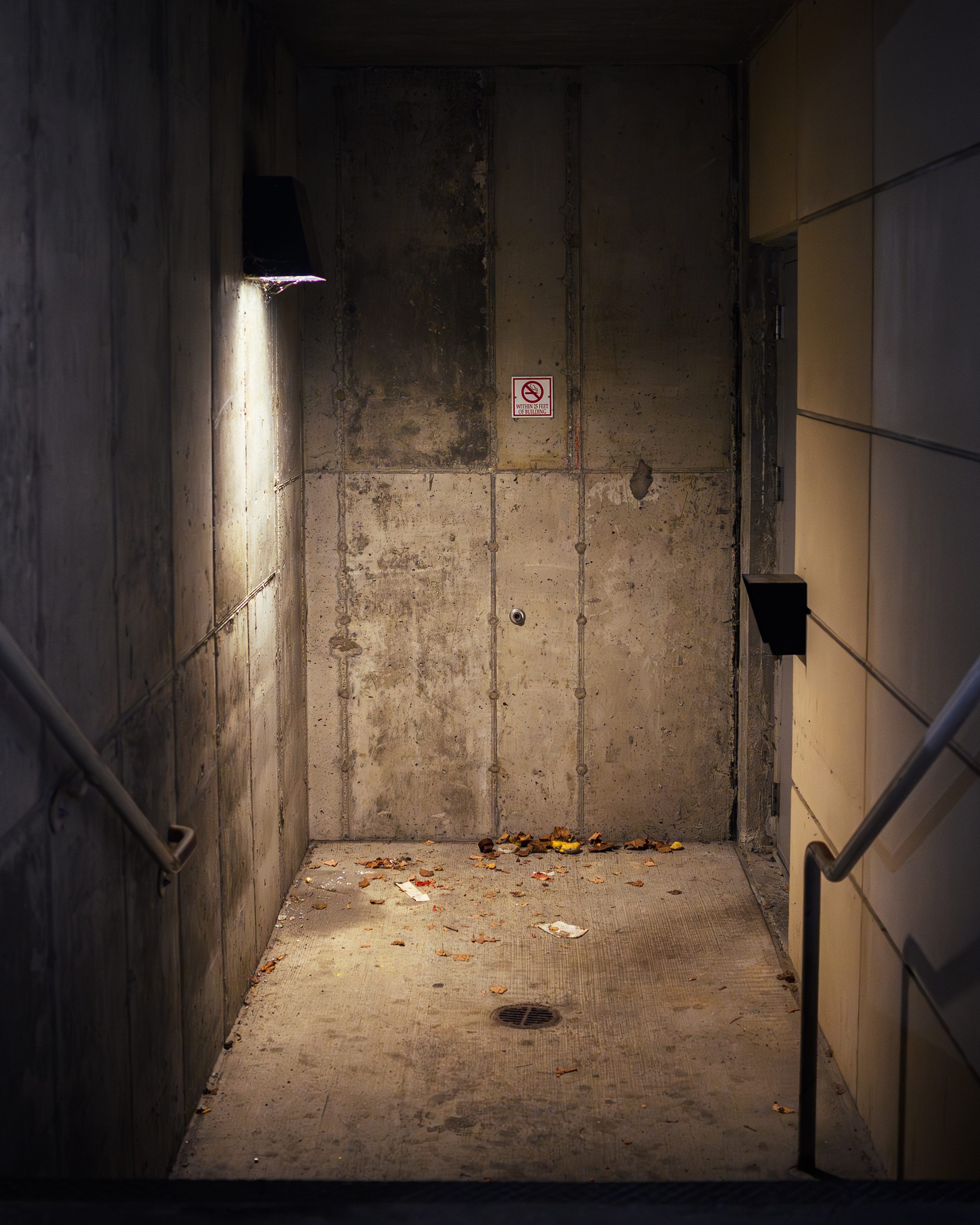 A concrete service passage lit by a single fixture, the far end empty.