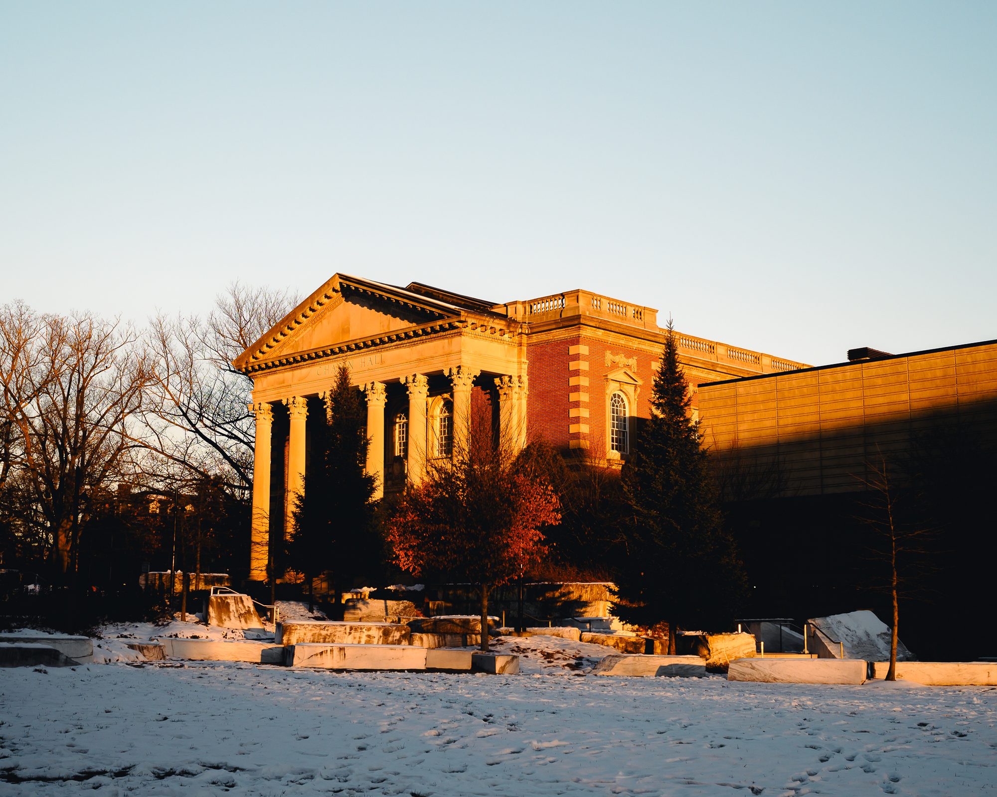 Chapin Hall from further back in the same light, contractors' equipment parked along the snow line.