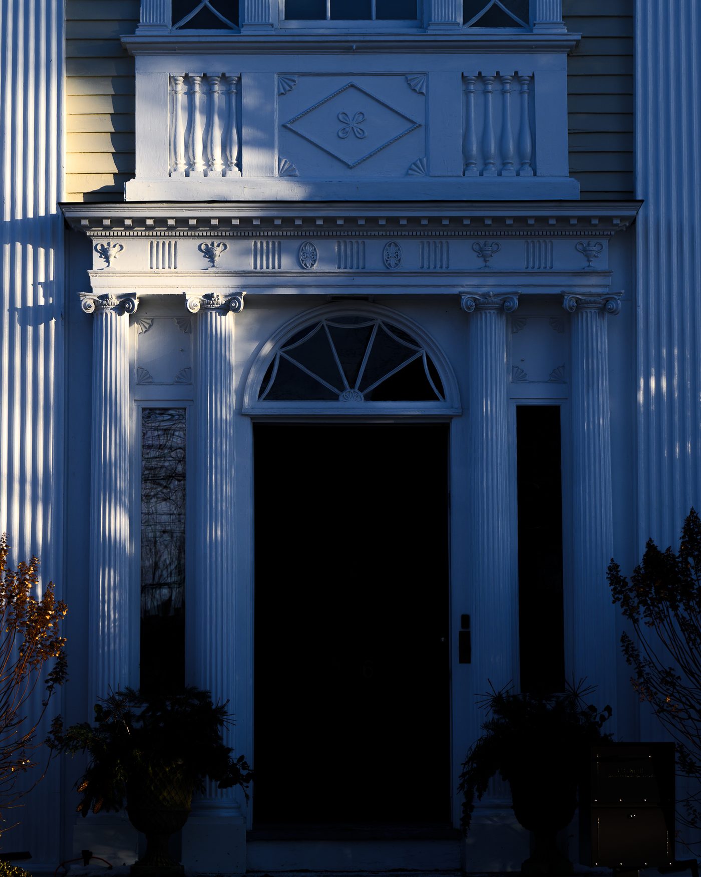 The front of Mauds House in blue shadow, its doorway a black rectangle, pilasters catching the last light.