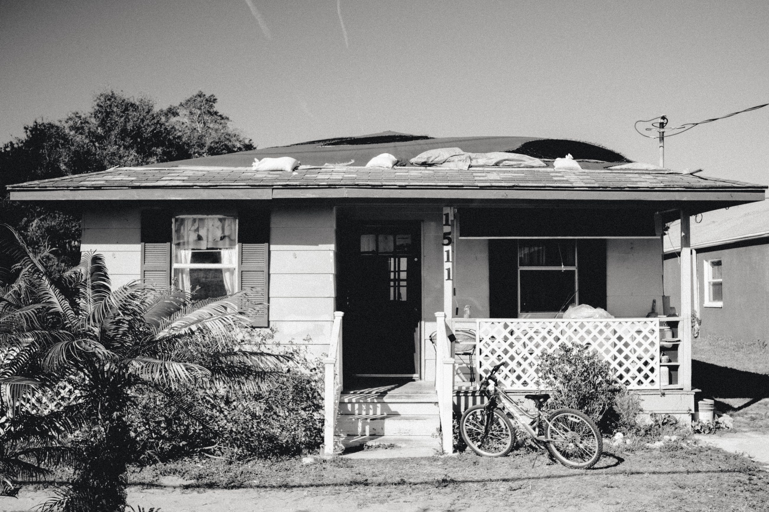 A single-storey house with a porch and white lattice skirting. A bicycle leans against the front.