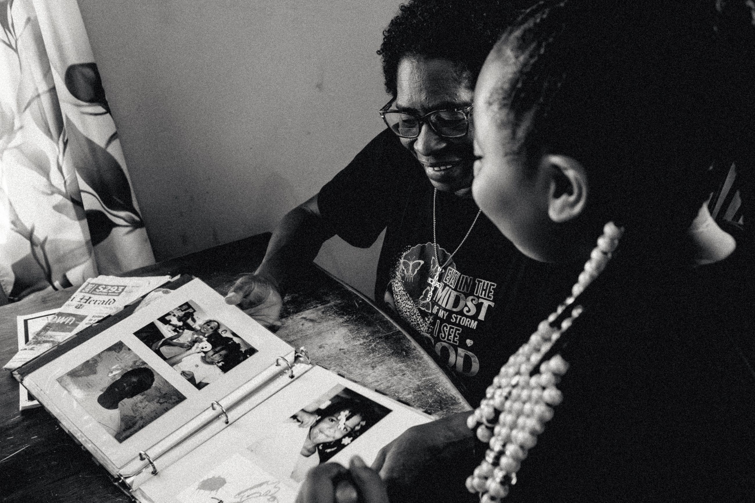 A woman and a child leaning together over an open photograph album.