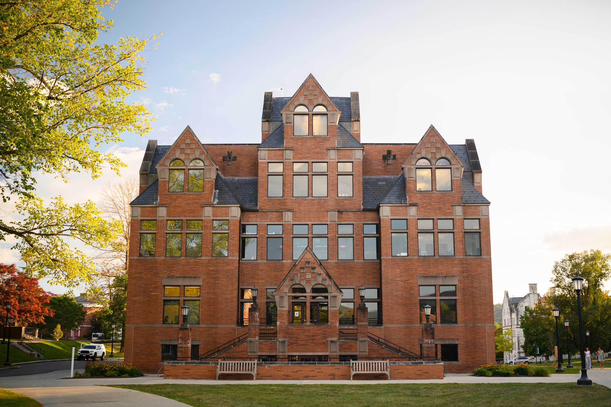 Hopkins Hall in red brick and gabled stone, spring trees at either side.
