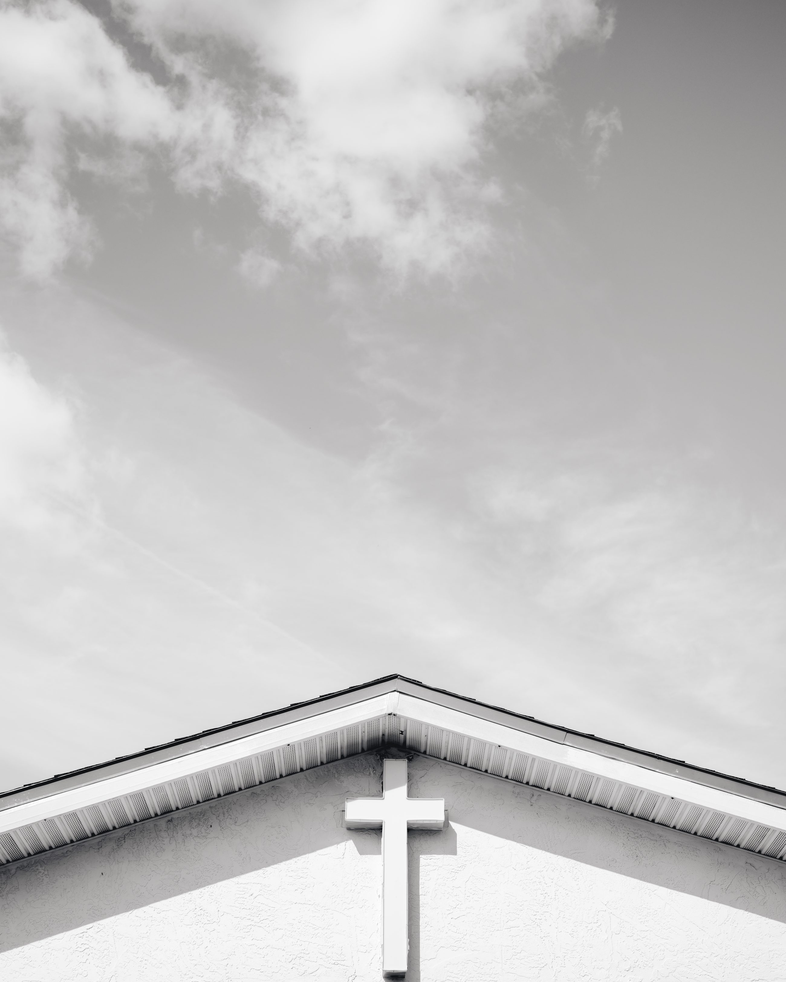 A cross on the chapel roofline against an open sky.