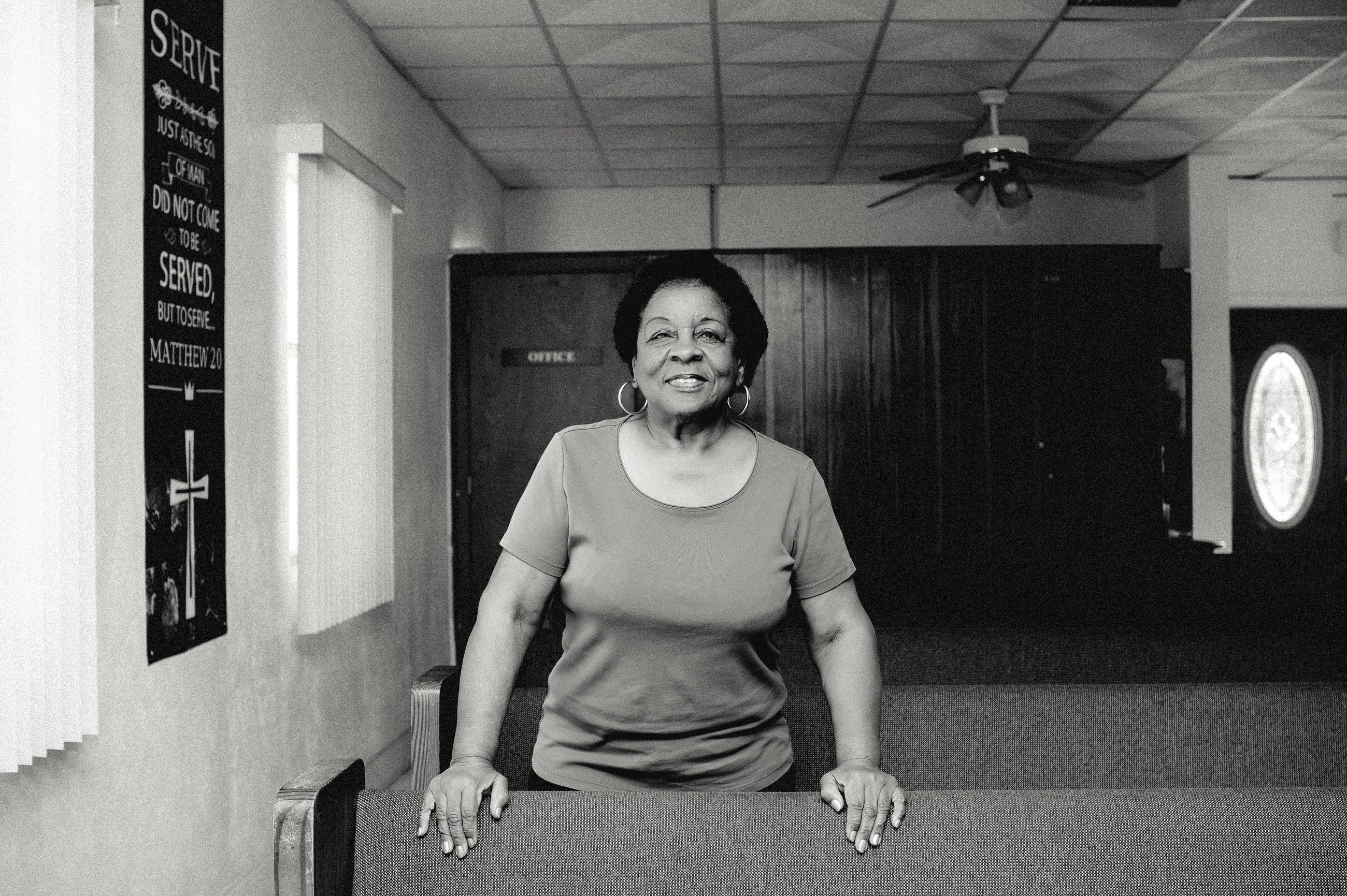 A woman standing in the aisle of the empty church.