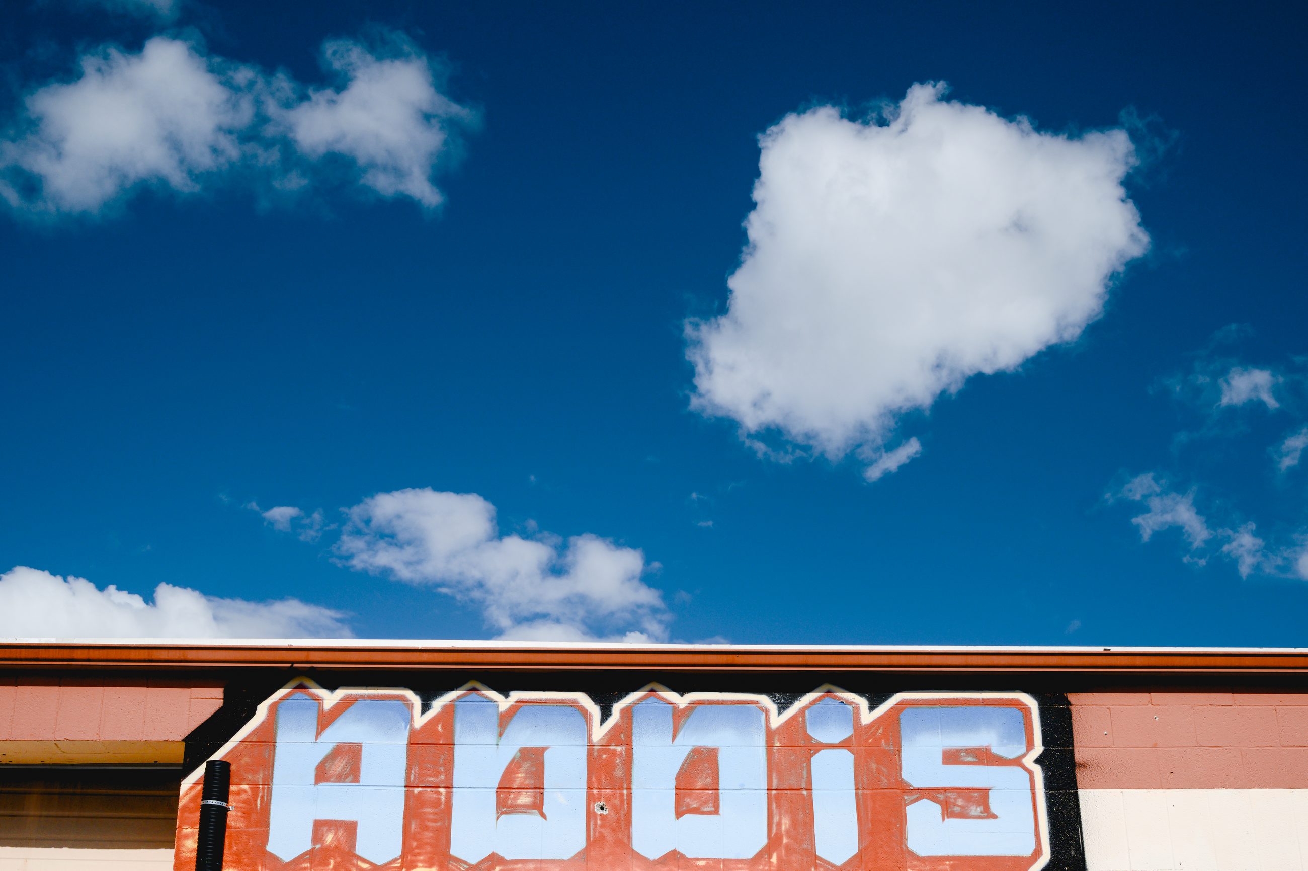 The word ADDIS in tall painted letters across an orange building front, a single cloud in a blue sky above it.